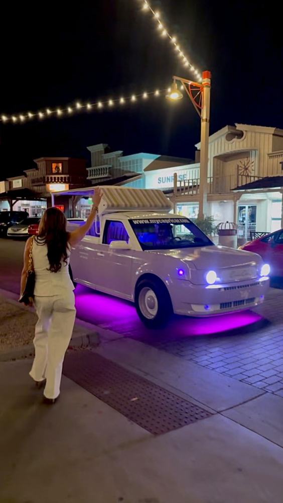 The lavender Capri Car glowing under Old Town string lights